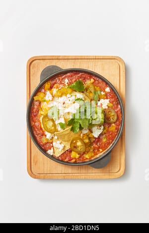Piatto Shakshuka con pita in una padella su un asse di legno. Foto Stock