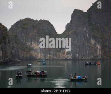 Una vista di prima mattina della Baia di ha Long con barche da pesca locali tra le formazioni rocciose di calcare, Foto Stock