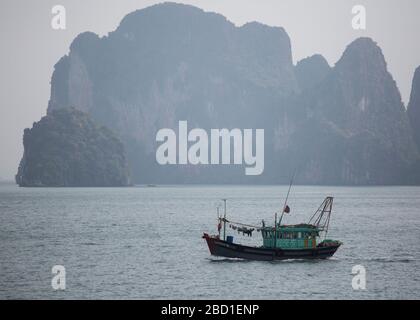 Una vista di prima mattina della Baia di ha Long con barche da pesca locali tra le formazioni rocciose di calcare, Foto Stock