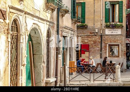 La gente mangia fuori un piccolo ristorante a conduzione familiare, al Ponte Storto Osteria vicino al ponte sul canale di Ponte Storto, in una tranquilla strada secondaria di Venezia Foto Stock