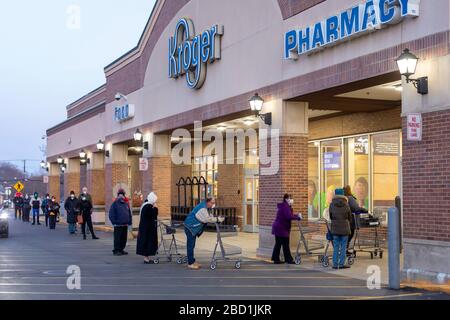 Grosse Pointe Woods, Michigan, Stati Uniti. 6 Aprile 2020. Gli anziani, la maggior parte dei quali indossano maschere facciali, si allineano all'alba, in attesa dell'apertura di un supermercato Kroger. A causa della pandemia di coronavirus, la prima ora dopo l'apertura è riservata agli anziani, alle donne in gravidanza e ai soccorritori. Credit: Jim West/Alamy Live News Foto Stock