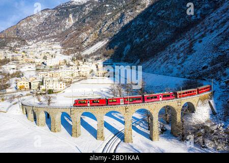 Bernina Express passa sopra il viadotto elicoidale (spirale) di Brusio, Patrimonio dell'Umanità dell'UNESCO, Valposchiavo, Canton Graubunden, Svizzera Foto Stock
