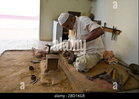 Campaniere musulmano che batte il rame in forma per fare campane a mano per il bestiame o per la casa, villaggio di Nirona, Gujarat, India, Asia Foto Stock