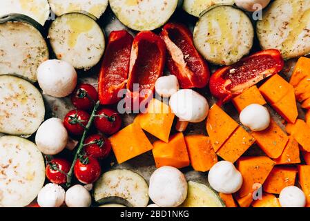 Cena Detox salutare con verdure diverse come melanzane, pepe rosso, pomodori ciliegini, zucca alle butternut, funghi. Fette di verdure crude preparate per la torrefazione, semplice pasto di famiglia Foto Stock