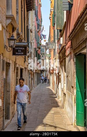 Un uomo che cammina lungo Calle seconda del Cristo una stradina nel quartiere di Dorsoduro a Venezia Foto Stock