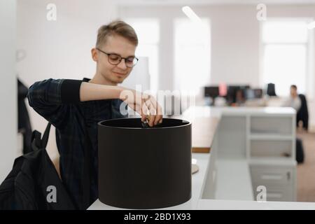 Il giovane che mette una batteria nel riciclaggio può in ufficio. Concetto ambientale ecologico e sostenibile dell'ufficio. Foto Stock
