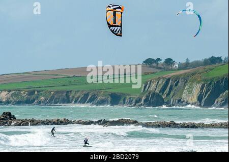 Garrettstown, West Cork, Irlanda. 6 Aprile 2020. Due kite surfisti godono dei forti venti e delle grandi onde a Garrettstown Beach, mentre osservano le linee guida del governo sulle distanze sociali durante la pandemia di Covid-19. Credit: Andy Gibson/Alamy Live News Foto Stock