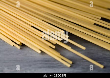 Spaghetti gialli lunghi su sfondo blu. Spaghetti bolognese crudi. Carta da parati spaghetti cruda. Concetto di base del cibo. Primo piano Foto Stock