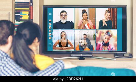 Coppia millenaria che si diverte in videochiamata da casa con amici multirazziali di tutto il mondo grazie alla quarantena di isolamento a distanza sociale Foto Stock