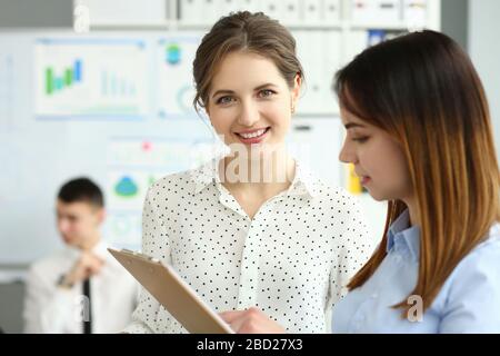 Bella donna sorridente che guarda in macchina fotografica durante il processo di lavoro in ufficio Foto Stock