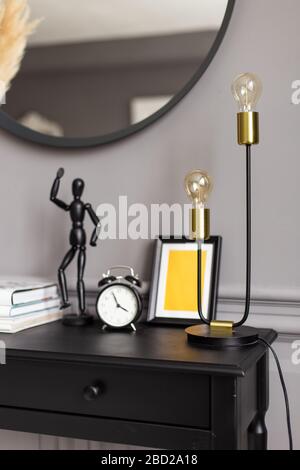 Console con uno specchio sullo sfondo di una parete grigia in un interno moderno Foto Stock