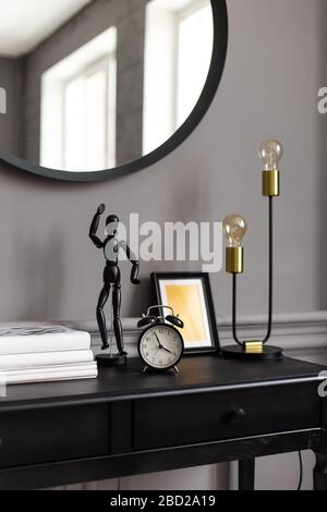 Console con uno specchio sullo sfondo di una parete grigia in un interno moderno Foto Stock