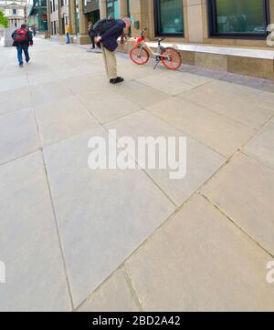 Londra, Inghilterra, Regno Unito. Un uomo che guarda una bici a noleggio "mobike" a Peter's Hill, vicino a St. Pauls Foto Stock