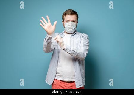 L'uomo in una maschera medica indossa guanti in lattice, è sicuro di essere in grado di proteggersi da un virus. Concetto di salute. Foto Stock