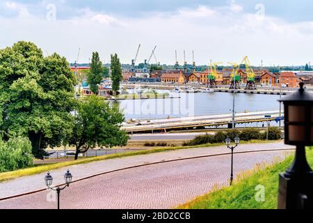 Vista da Rampart of Brave sul molo della Città Vecchia nei docklands di Szczecin con il fiume Odra, rustiche gru portuali chiamate Dzwigozaury e porto sullo sfondo Foto Stock