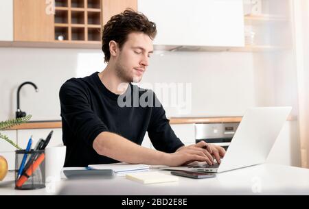 Giovane uomo che lavora a casa. Concetto di ufficio domestico e di lavoro in remoto Foto Stock