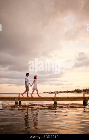 Felice metà adulto giovane camminando mano nella mano lungo un molo. Foto Stock