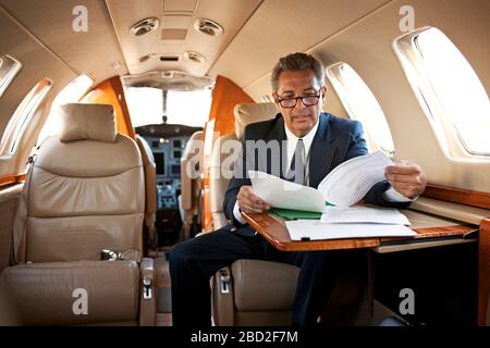 Imprenditore la lettura di alcuni documenti su un jet privato Foto Stock