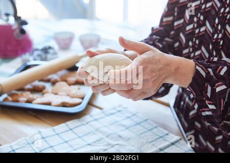 Le mani femminili di una donna anziana impastano l'impasto. La nonna fa i biscotti. Sfondo chiaro. Senza volto. Foto Stock