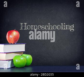 Homeschooling scritto su una lavagna vintage con mele e libri. Foto Stock