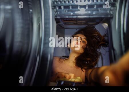 Uno sguardo all'uomo dalla lavatrice. La ragazza raggiunge per la lavanderia in lavatrice con caricamento verticale. Foto Stock
