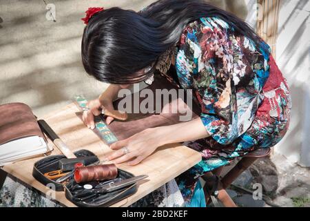 Mertola, Alentejo, Portogallo - 20 maggio 2017: Una donna artigiana lavora la pelle in un mercato di strada che si tiene a Mertola, nell'Alentejo portoghese Foto Stock