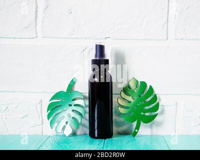 black bottle with sunscreen, antiseptic, sunscreen, empty bottle against a brick wall Foto Stock