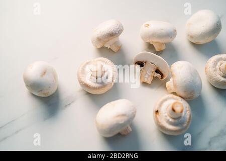 Set di funghi di champignon freschi interi e tagliati isolati su fondo di pietra bianca. Vista dall'alto Foto Stock