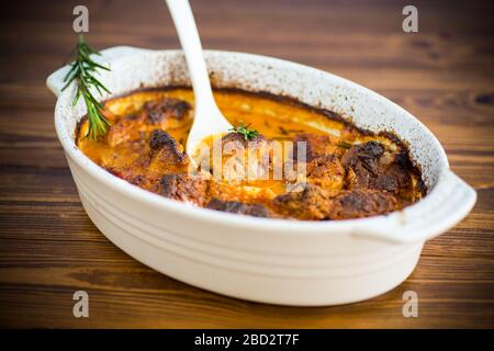 carne al forno con spezie verdure e sugo in ceramica, su un tavolo di legno Foto Stock
