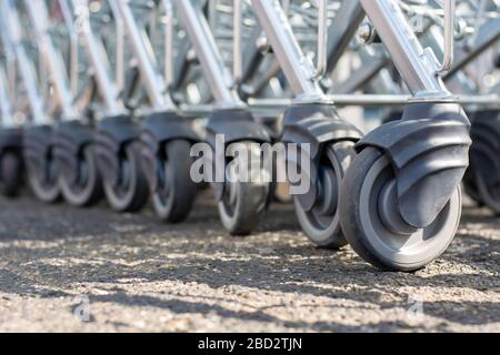 Ruote moderne del carrello della spesa del supermercato in una fila. Molte ruote in gomma dei carrelli per acquisti. Foto Stock