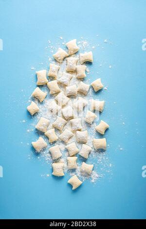 Gnocchi crudi fatti con formaggio e farina su fondo blu senza cuciture. Gnocchi al formaggio crudo a disposizione. Pasta tradizionale italiana. Foto Stock