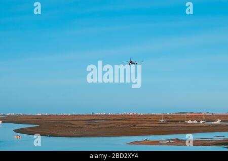 L'aereo vola verso l'aeroporto sul fiume nella città di Faro in Portogallo. Molte barche in una giornata di sole sul fiume. Foto Stock