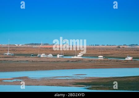 L'aereo vola verso l'aeroporto sul fiume nella città di Faro in Portogallo. Molte barche in una giornata di sole sul fiume. Foto Stock