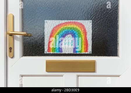 Disegno di un arcobaleno bloccato ad una porta d'ingresso durante la pandemia Covid-19 del 2020, incoraggiando la gente a rimanere al sicuro rimanendo a casa, da Anna Anderson