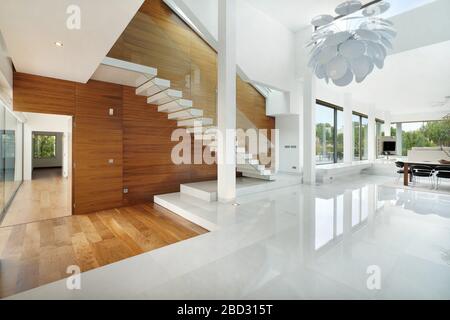 Interni domestici, camera moderna con mobili contemporanei. Accesso scale in legno al piano superiore. Foto Stock