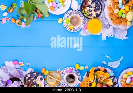 Pasqua colazione appartamento laici. Caffè aromatico fresco, farinata d'avena con frutti di bosco, biscotti, uova colorate e vari dolci pasquali. Vista dall'alto. Spazio di copia Foto Stock