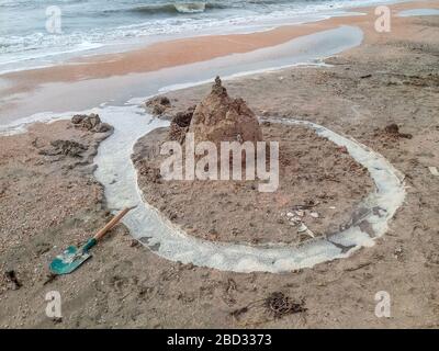 Castello di sabbia sulla spiaggia con conchiglie. Giochi per bambini in mare. Foto Stock