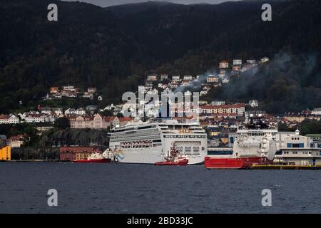 Nave da crociera Norwegian Spirit che si prepara a partire dalla banchina di Bontelabo, nel porto di Bergen, Norvegia. Un giorno grigio e piovoso. Due rimorchiatori stanno assistendo, il BB Foto Stock