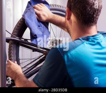 Il meccanico in un negozio di riparazione di biciclette oliatura della catena di una bicicletta. L'uomo mantenendo la sua bicicletta per la nuova stagione di guida. Il processo di lavorazione. Foto Stock