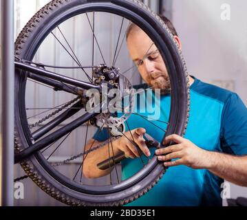 Il giovane gonfia la ruota della bicicletta utilizzando una pompa Foto Stock