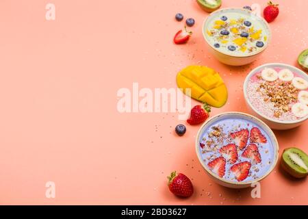 Bellissime ciotole multicolore per frullati salutari con frutti di bosco e supercibi su uno sfondo luminoso. Cibo estivo per il concetto di detox. Vista dall'alto, disposizione piatta, spazio di copia. Foto Stock