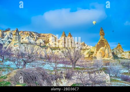 Paesaggio mozzafiato della Val Pifeon con rocce di tufo giallo brillante, antiche grotte, celle tagliate, frutteti e palloncini ad aria calda volanti, Pigeon Valley, Foto Stock