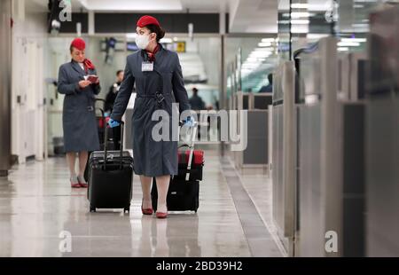 Un assistente di volo che indossa una maschera protettiva e guanti tows il suo bagaglio dopo la pulizia attraverso gli ufficiali della dogana e della protezione di confine degli Stati Uniti all'Aeroporto Internazionale di Dulles a Dulles, Va., 18 marzo 2020. In risposta alla pandemia di coronavirus, gli ufficiali della CBP hanno donato i dispositivi di protezione individuale (PPE) mentre lavorano in prima linea nella crisi. CBP Foto di Glenn Fawcett Foto Stock