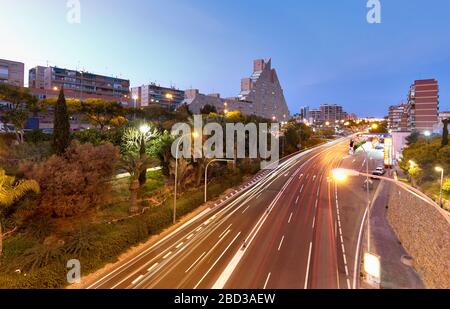 Alicante, Spagna. 21 febbraio 2020: Lunga esposizione crepuscolo in una strada con abbastanza traffico e sullo sfondo un edificio ben noto con il nome di Th Foto Stock