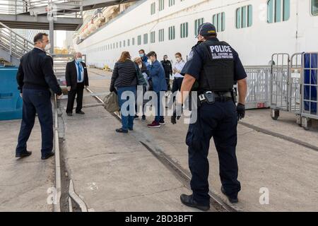 Gli ufficiali della dogana e della polizia di frontiera assistono i passeggeri che sbarcano la nave da crociera Celebrity Eclipse al Porto di San Diego il 3 aprile 2020 a San Diego, California. Più di duemila passeggeri sono stati sottoposti a screening e quindi autorizzati a partire in autobus e aerei per tornare a casa. Foto Stock