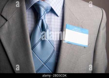 Primo piano di un nome in bianco tag bloccato al lapel della tuta di un uomo d'affari irriconoscibile Foto Stock