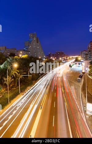 Alicante, Spagna. 21 febbraio 2020: Lunga esposizione crepuscolo in una strada con abbastanza traffico e sullo sfondo un edificio ben noto con il nome di Th Foto Stock