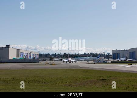 Un Dreamliner 787-8 per American Airlines viene trainato sulla Boeing Flightline presso la Boeing Factory di Everett, Washington, lunedì 6 aprile 2020. Boeing ha prorogato fino a nuovo avviso la sospensione temporanea delle operazioni di produzione in tutti i siti di Puget Sound e Moses Lake. In lontananza si trovano gli appendiabiti della fabbrica Boeing Everett, dove la maggior parte degli aerei a fusolatura larga di Boeing vengono verniciati prima della prova finale di volo. Foto Stock