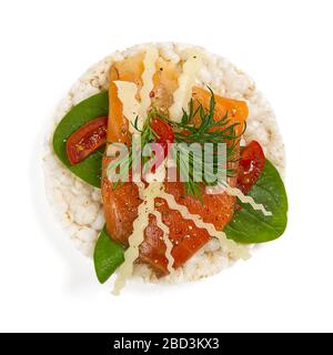 guarire cibo torta di riso sandwich isolato su sfondo bianco. Torte di riso con basilico, pomodori, formaggio e trota rossa o pesce salmone. Foto Stock