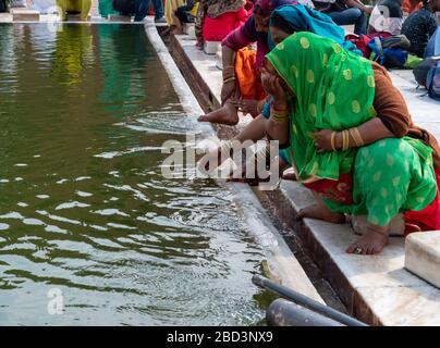 una donna in un sari verde lava il suo viso alla moschea jama masjid a delhi Foto Stock